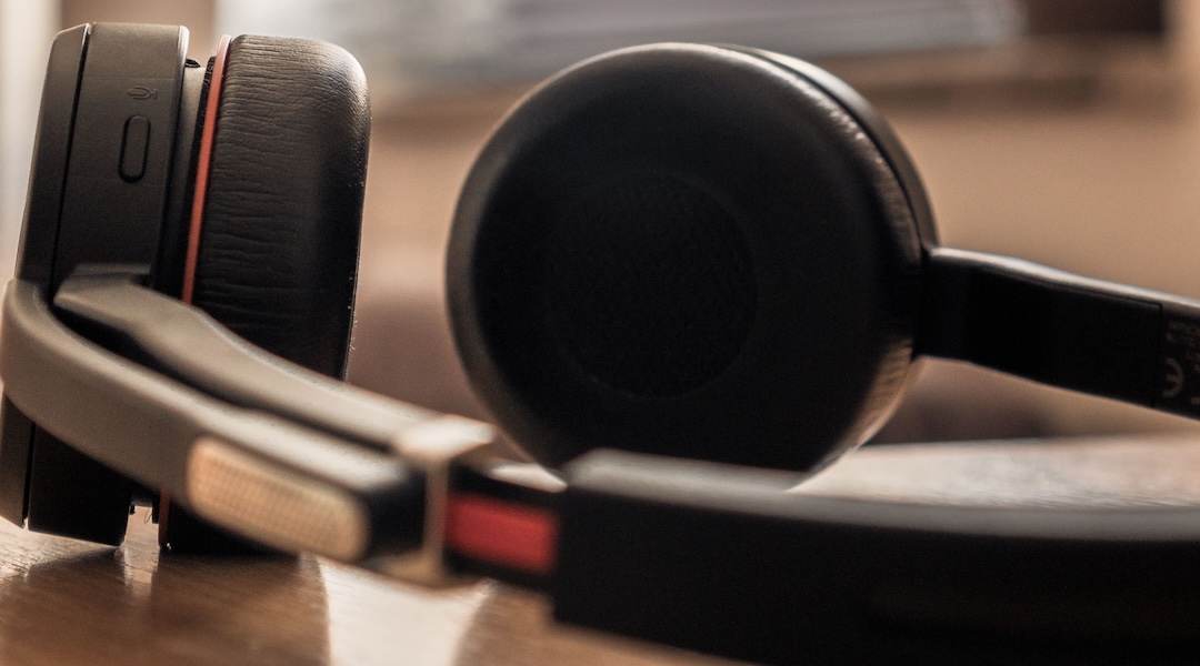 A close-up shot of black headphones on a wooden surface with soft background lighting.