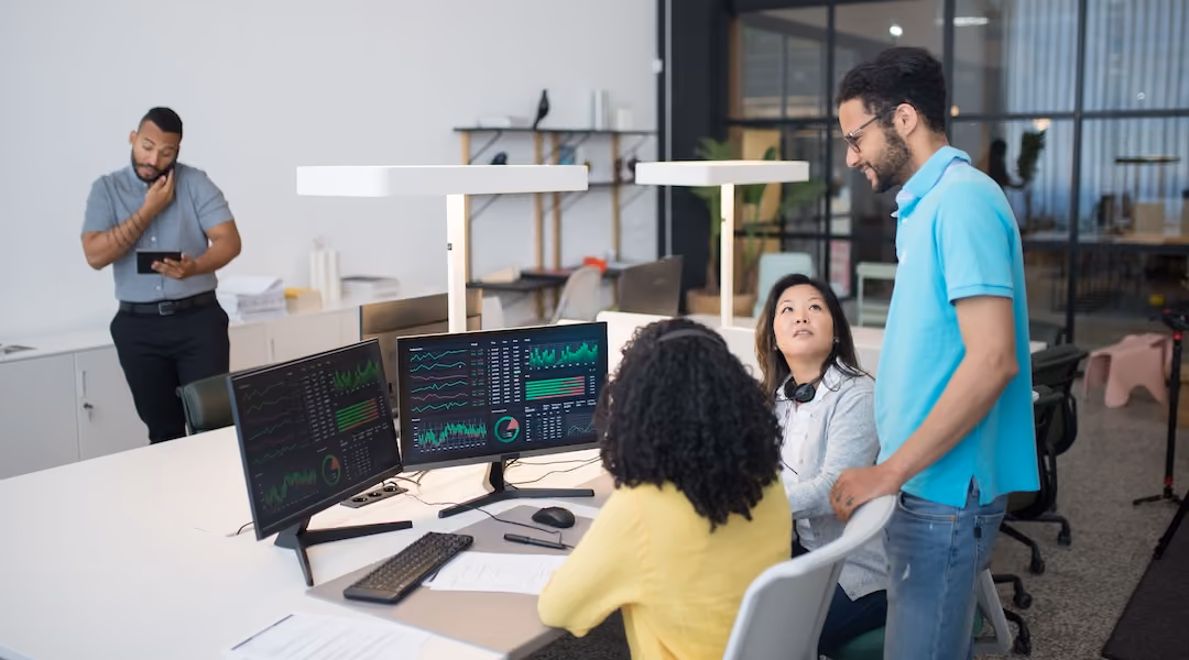Office employees collaborate on financial data at modern workspace, engaging in teamwork and communication.