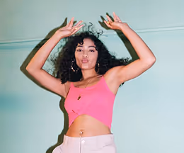 A woman in a pink top and white shorts.