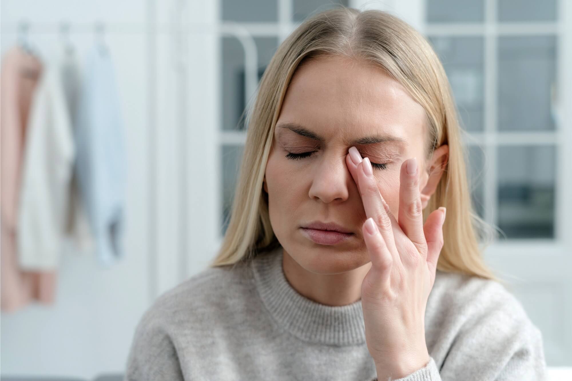 Woman with closed eyes rubbing her temple.