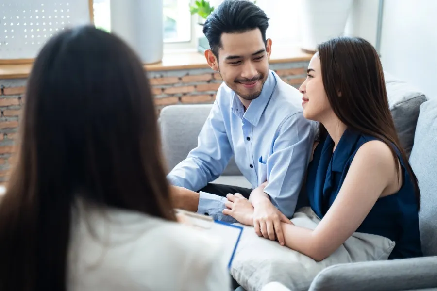 Couple holding hands and smiling during a counseling session with a therapist.