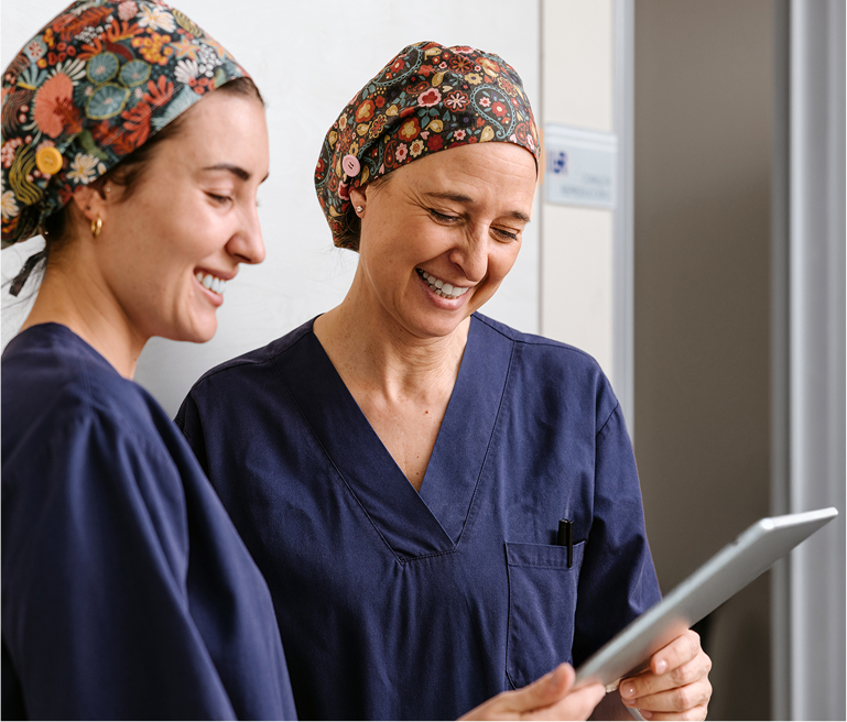 Two nurses in scrubs looking at a clipboard
