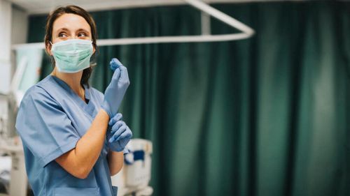 A nurse putting on surgical gloves