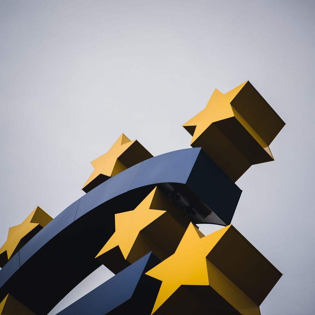 Euro-Skulptur mit gelben EU-Sternen vor grauem Himmel