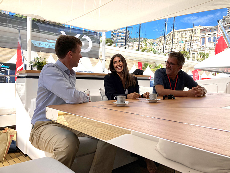 Drei Personen im Gespräch an Bord einer Yacht im Hafen