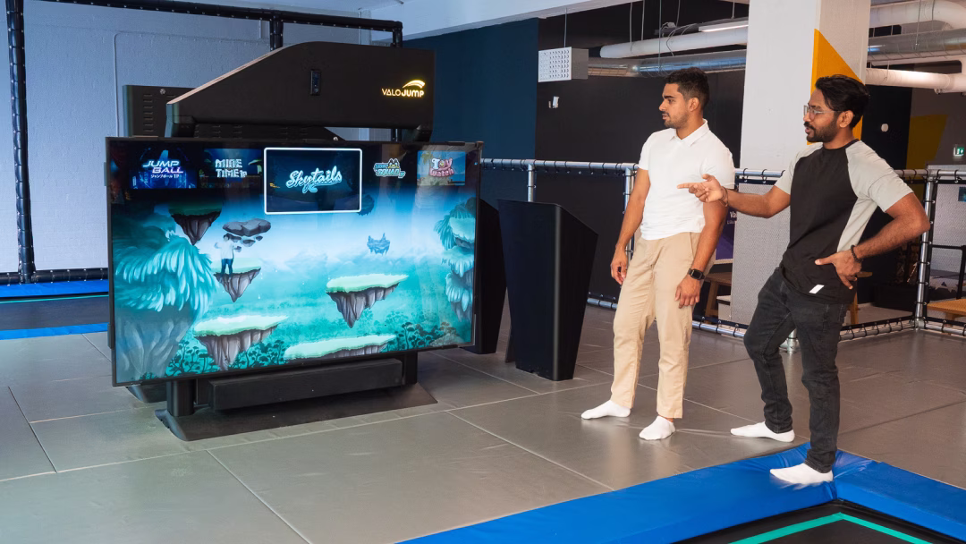 Two people looking at the ValoJump 86 screen showing a video preview of one of the games in attract mode.