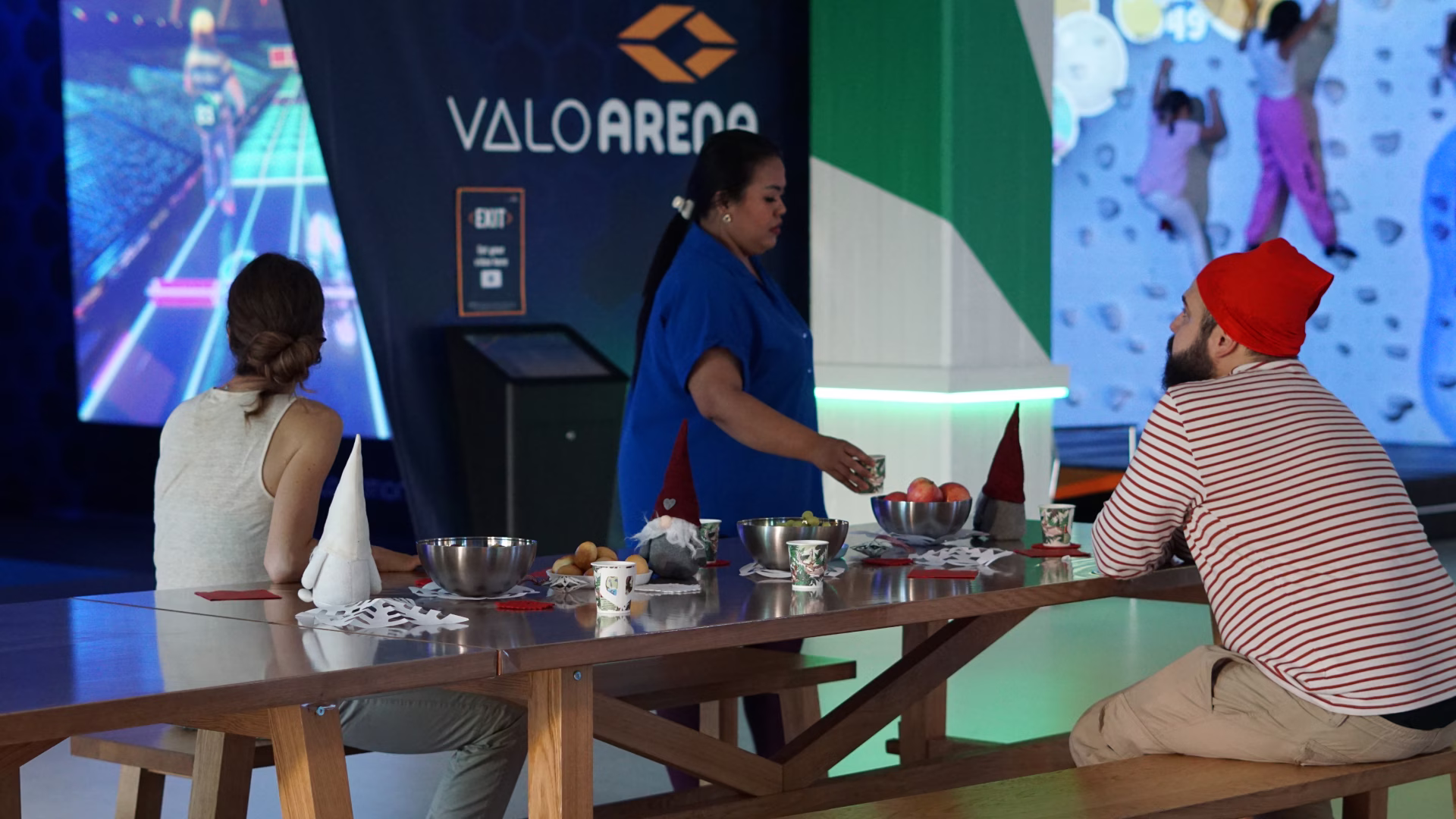 Adults around a table with christmas decorations. Children climbing on ValoClimb in the background.
