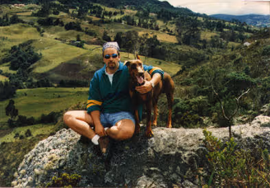 A young Ed Denyer, founder of Eco Coffee, sat near a mountain view with his dog