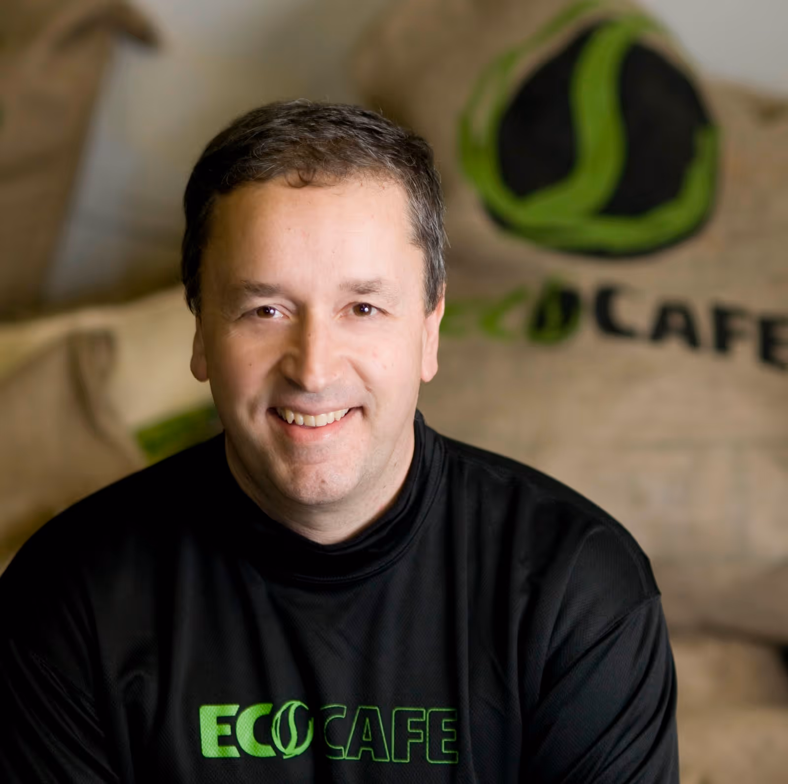 Ed Denyer, founder of Eco Coffee, with a stack of branded cloth coffee bags behind him