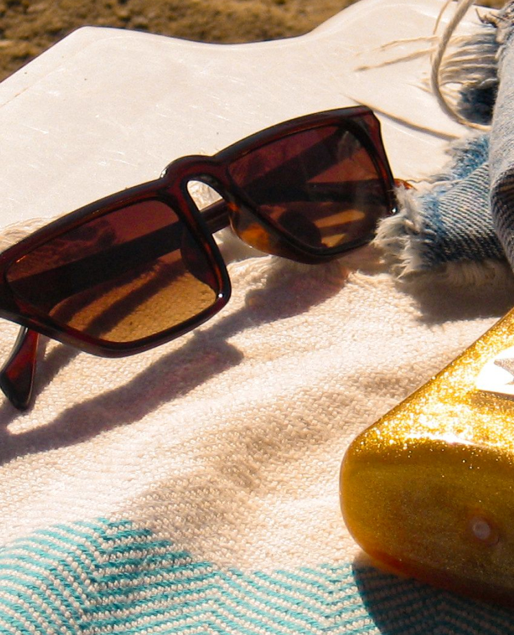 sunglasses and sunscreen on beach