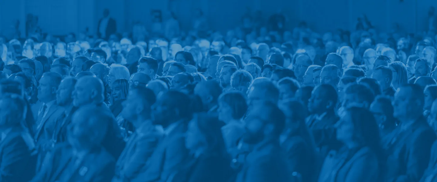 Large audience of diverse people seated closely together at an indoor event.