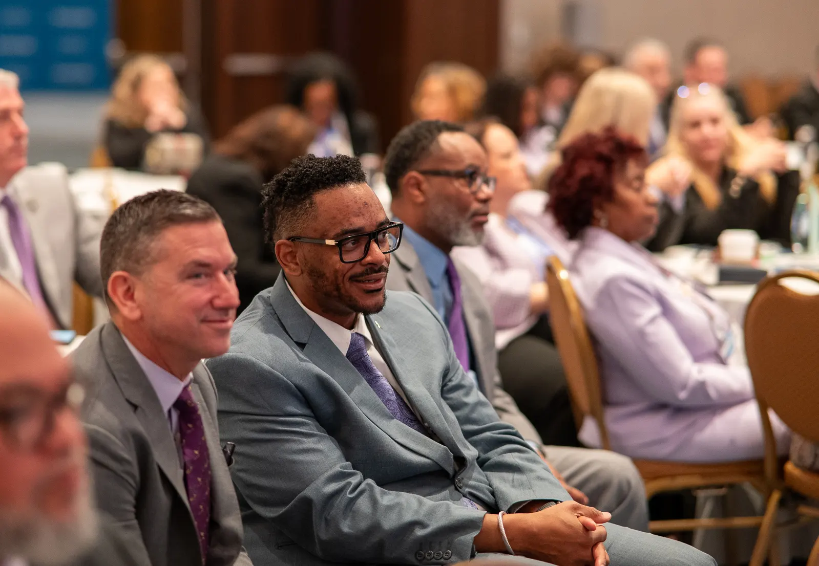 Audience of professionally dressed men and women attentively listening at a conference or seminar.