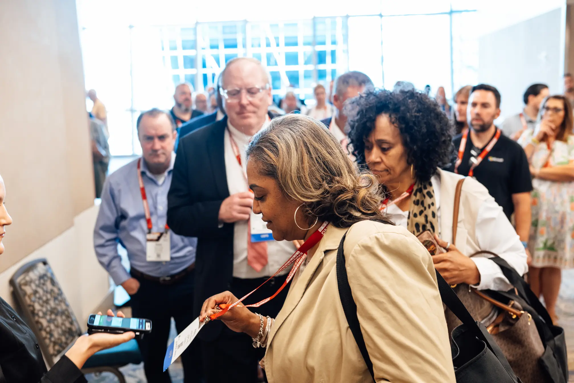 Audience members attentively listening at a formal event, seated at round tables with name tags.