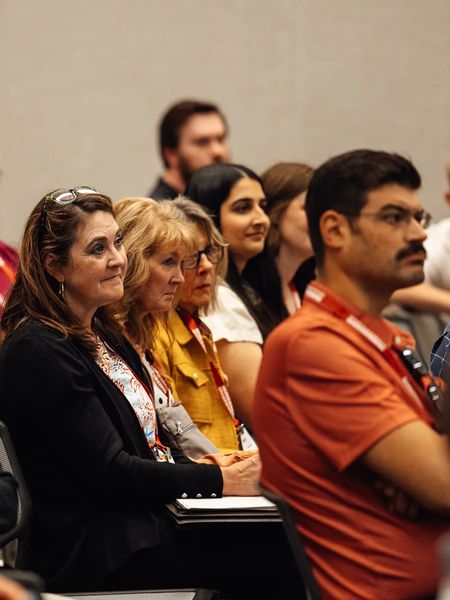 Group of people sitting attentively in a conference or seminar setting.