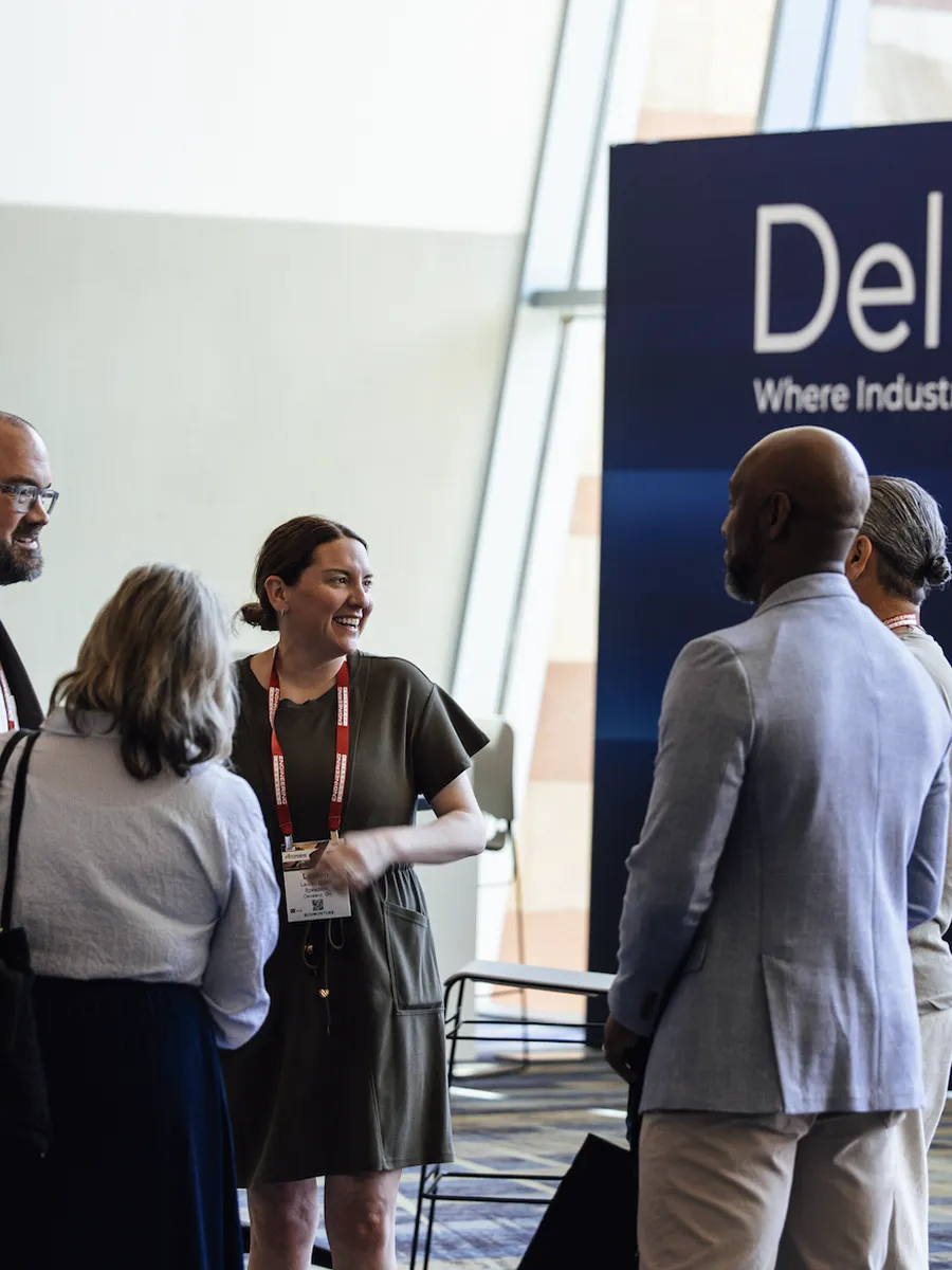 Group of diverse people talking and smiling at a conference or networking event indoors.