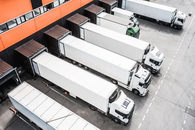 Trailer repair with multiple box trailers backed into loading docks for inspection and maintenance at distribution facility.