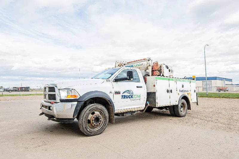 Mobile repair service truck with TruckZone branding and crane body parked at a heavy-duty repair facility.