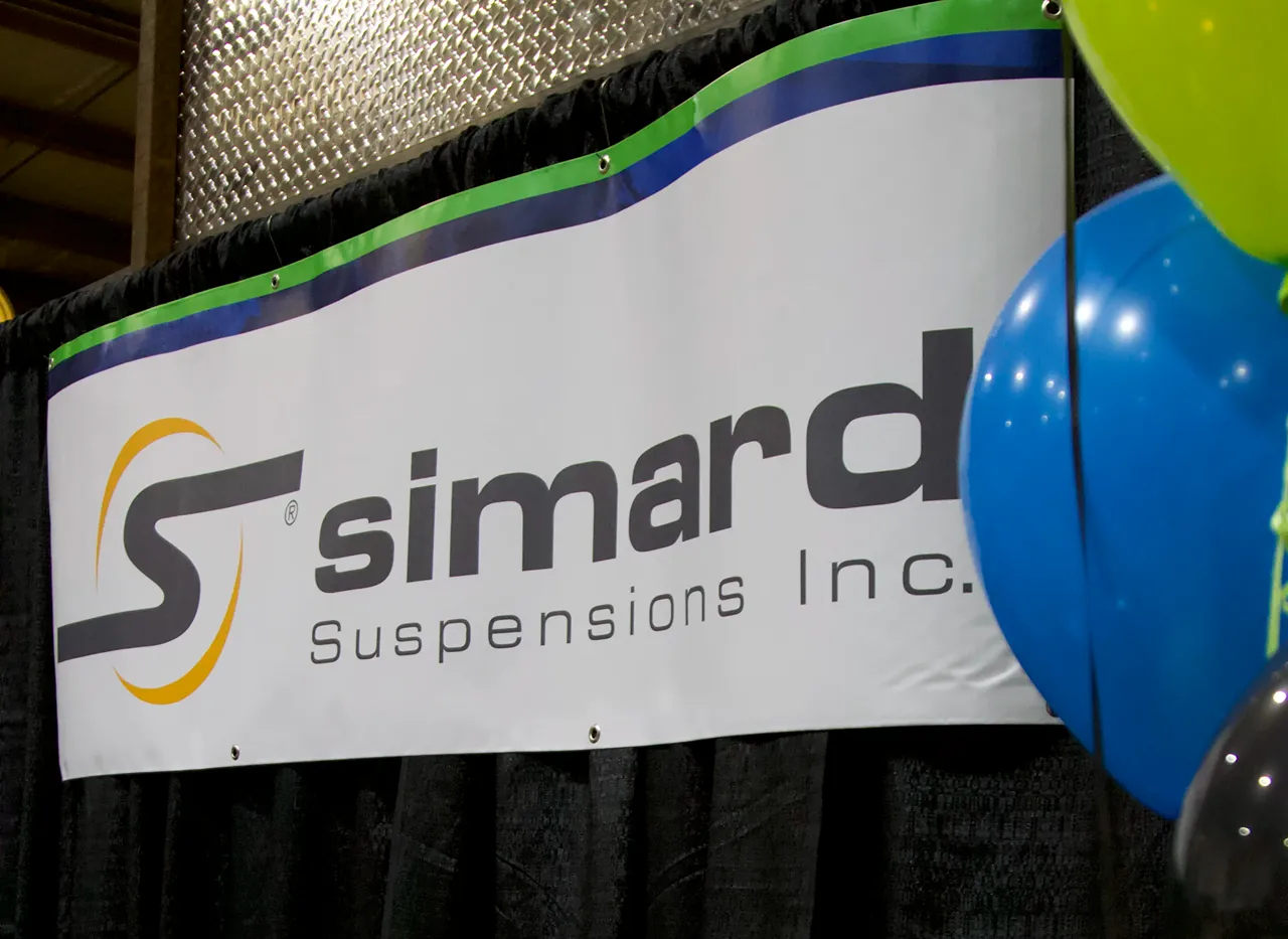Simard Suspensions Inc. banner with blue and green balloons at a heavy-duty truck industry event.