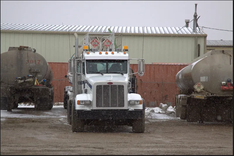 Oilfield trucks parked in a snowy heavy-duty yard, with tanker markings 1267, 1287, and 1017 visible.