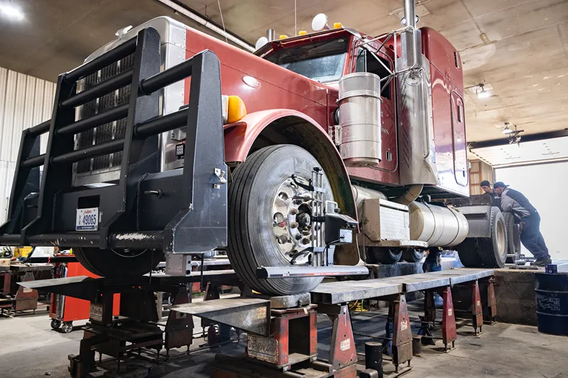 Frame straightening service on a heavy-duty semi truck positioned on a repair rack inside the shop.