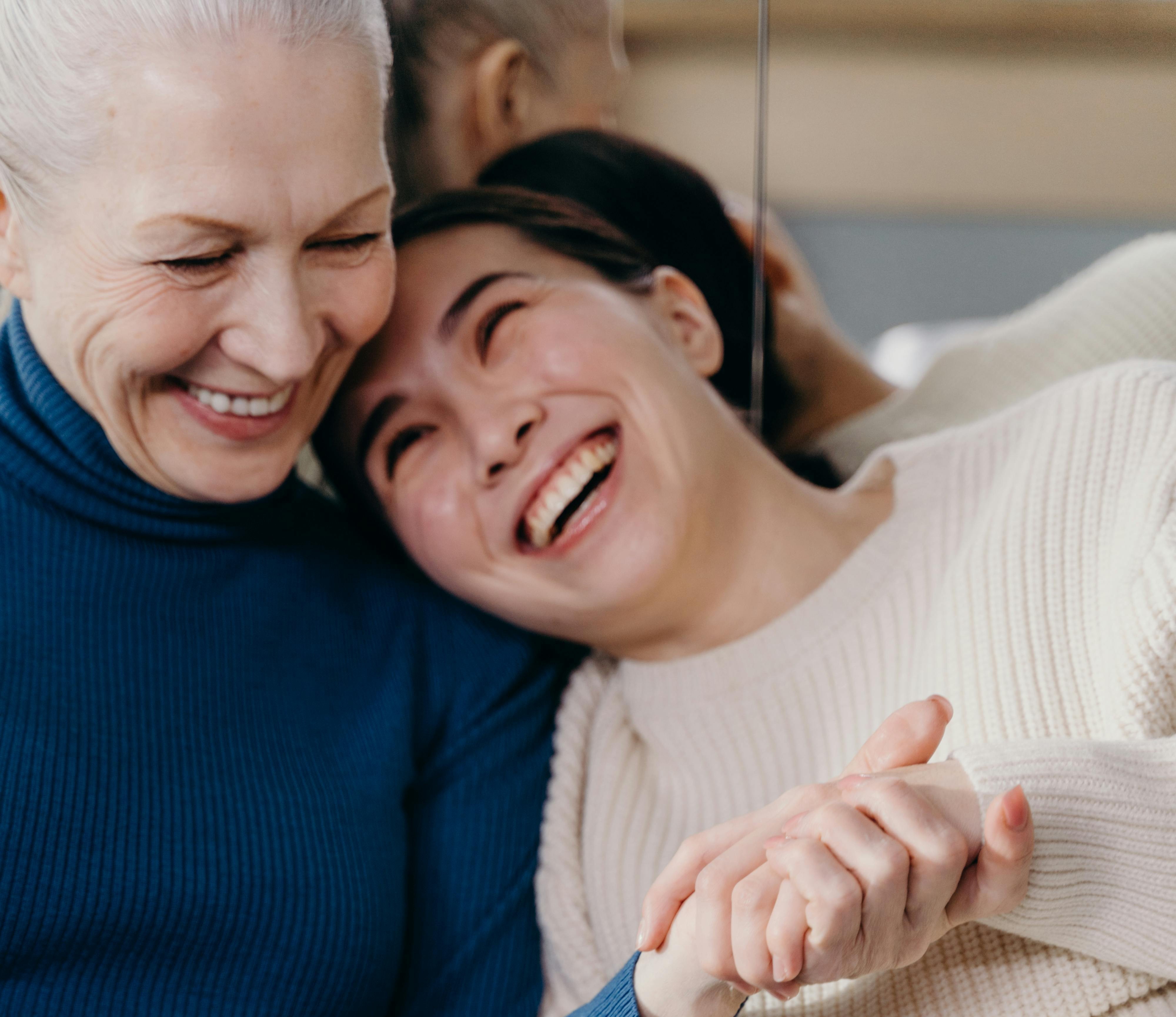 Older mother and adult daughter laughing and hugging.