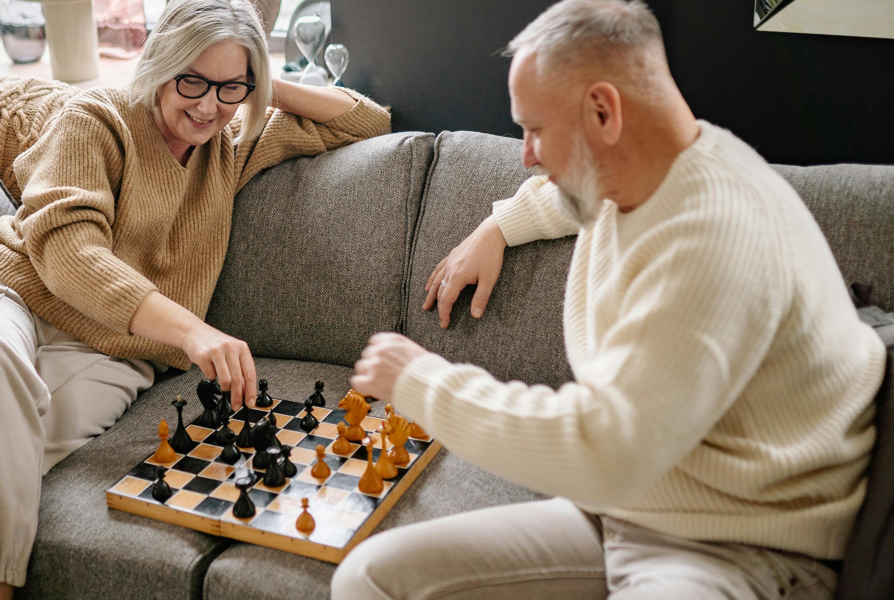 Older couple playing chess on the sofa.
