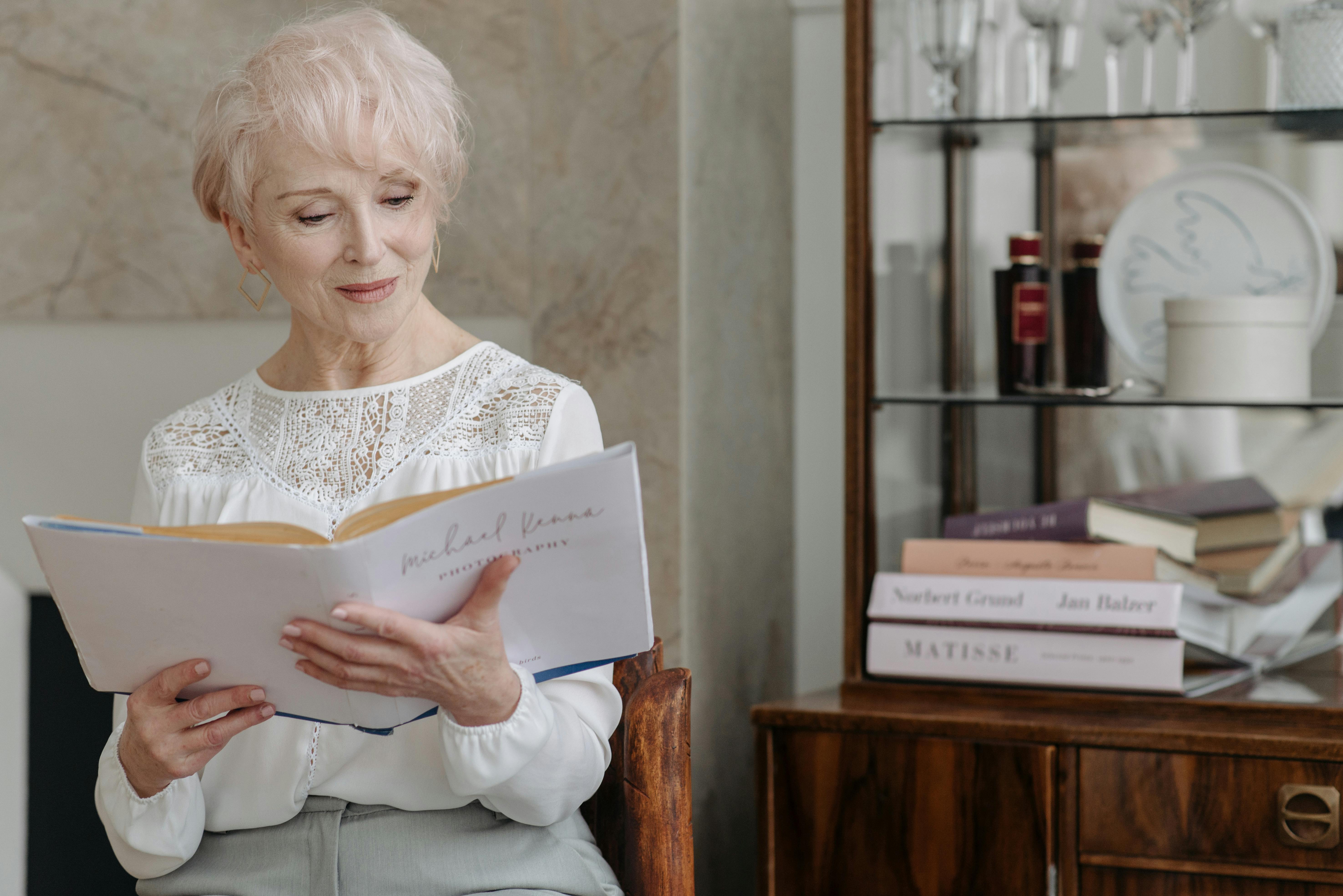 Older woman reading a book in her living room.