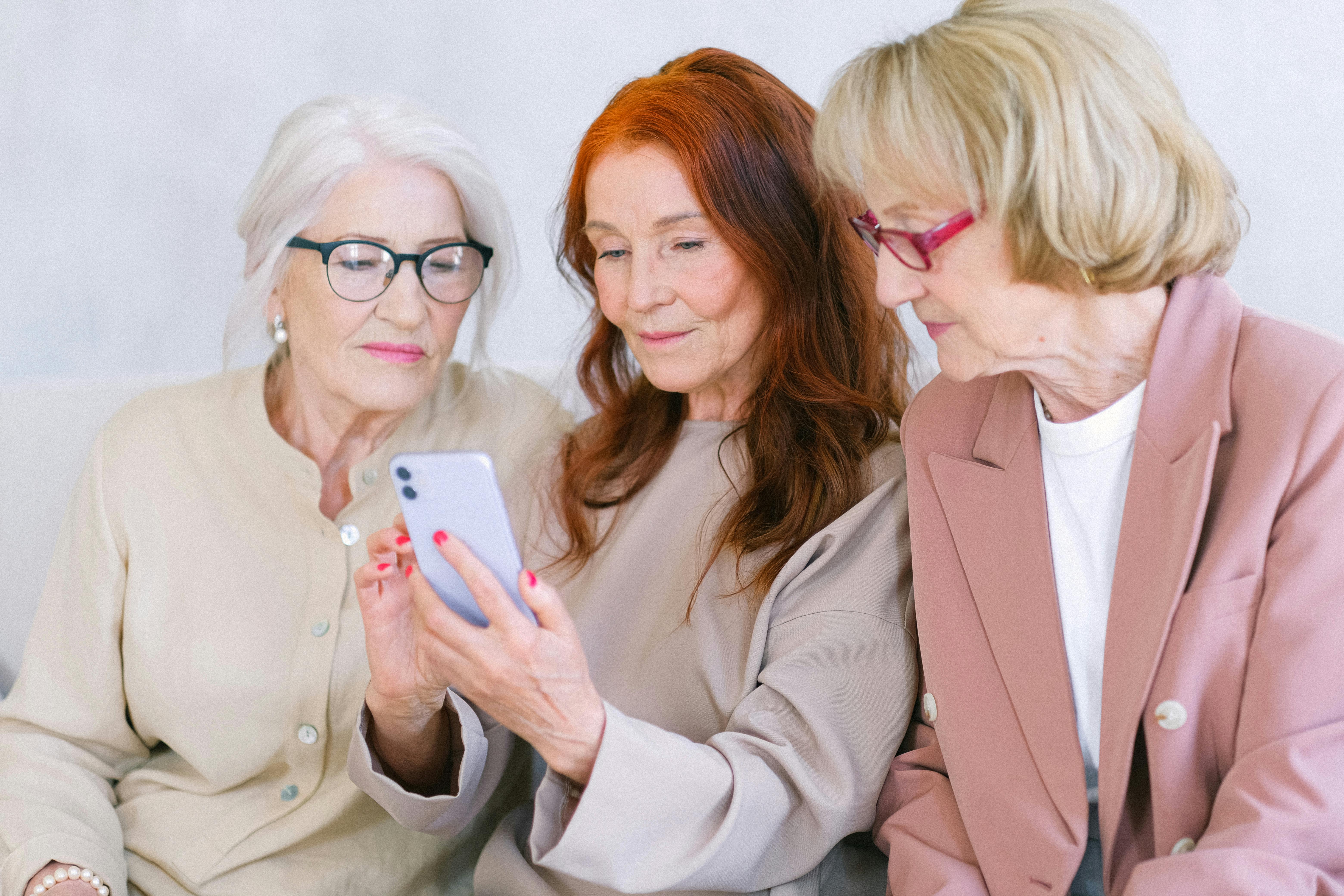 Three older women looking at a smartphone together.