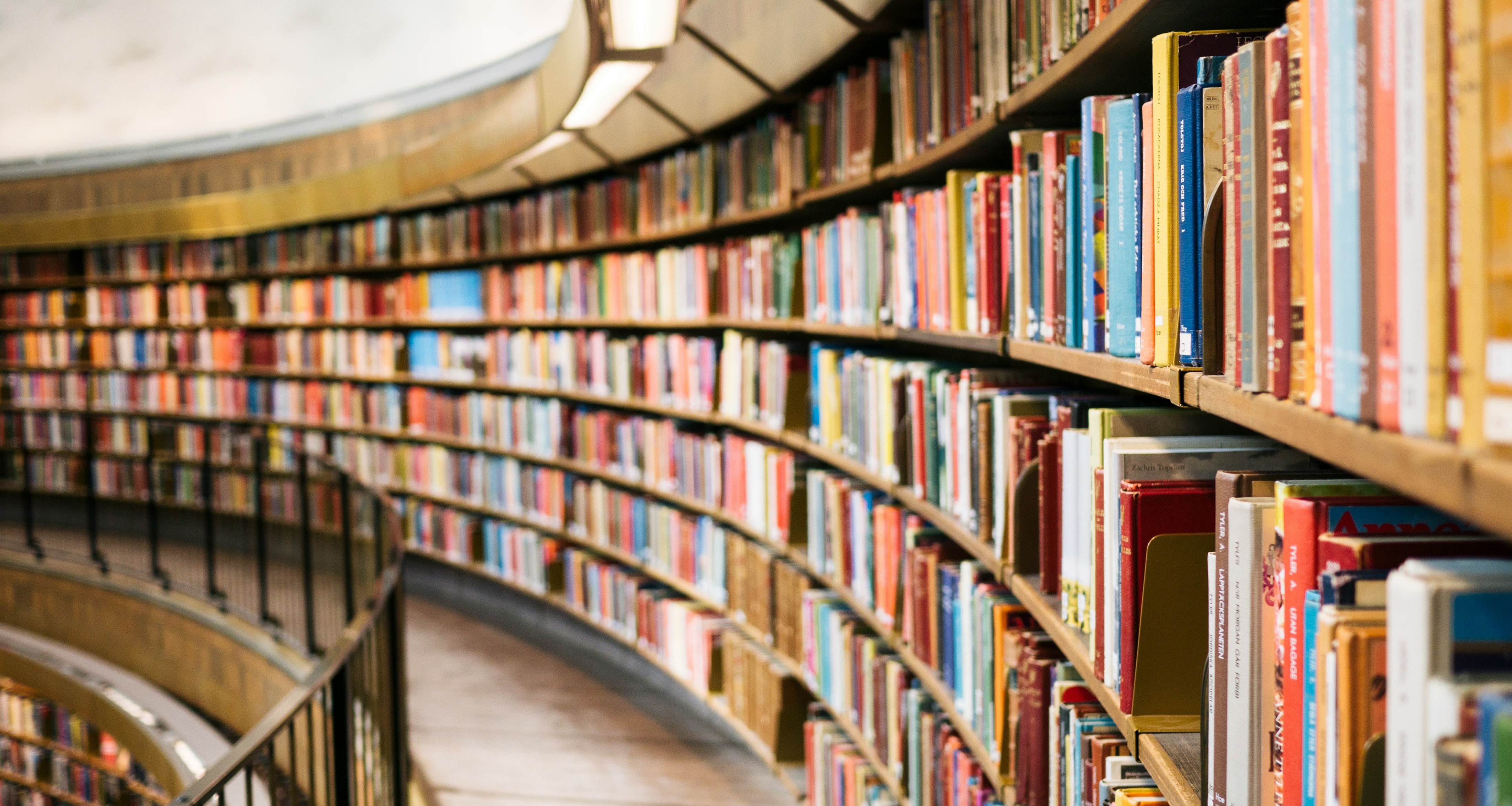 A picture from inside a library with tons of books in the shelves.