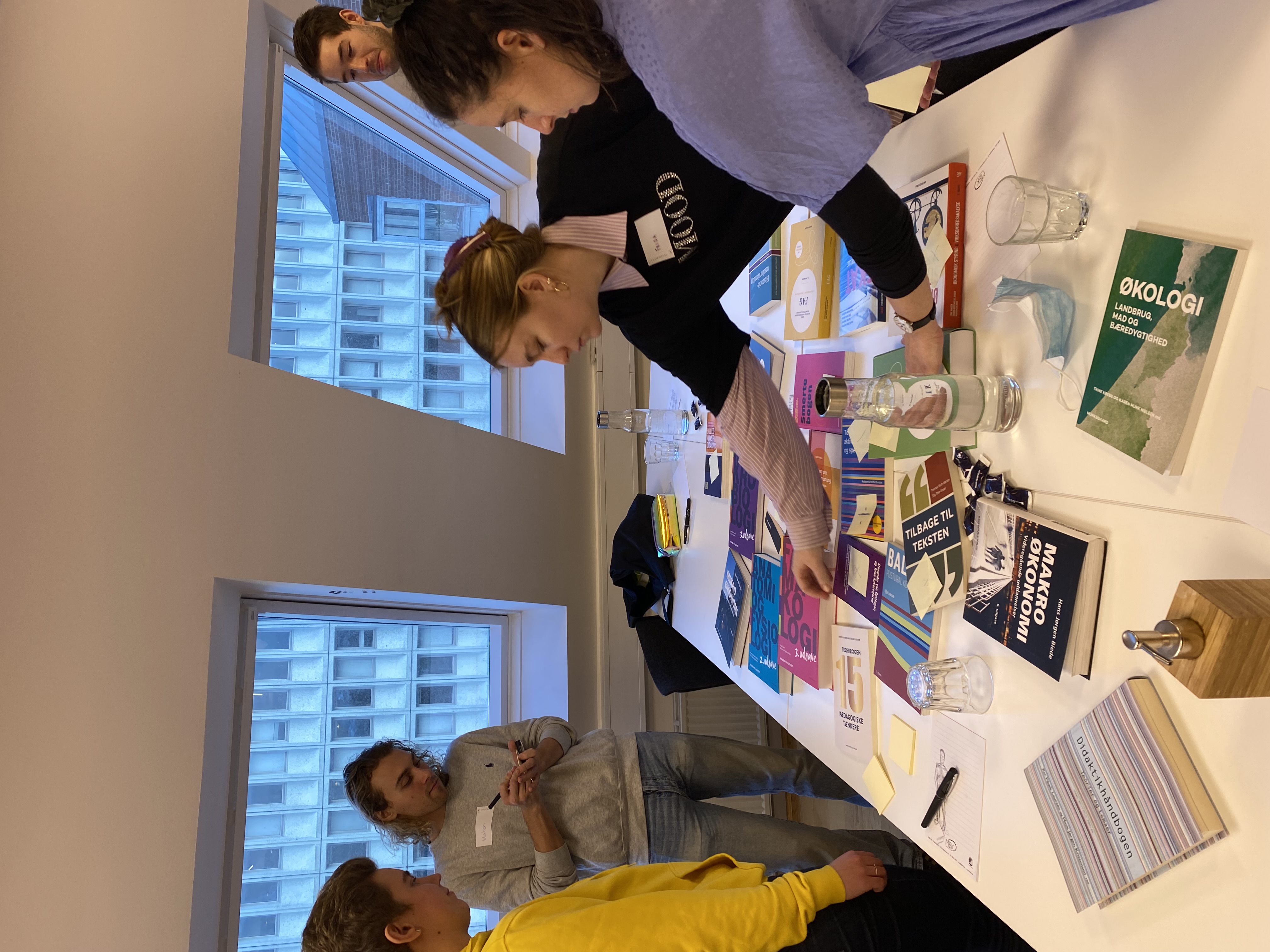 Five higher education students sharing feedback and discussing the textbooks from Gyldendal