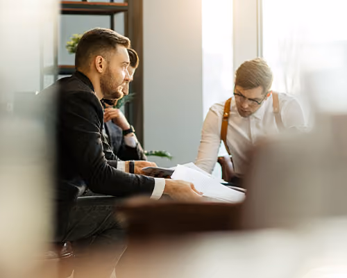 Two businessmen reviewing paperwork together in a bright, modern office