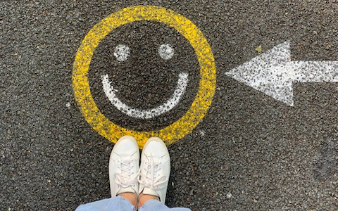 Photo of a street floor with a smiling graffiti painted on the pavement.