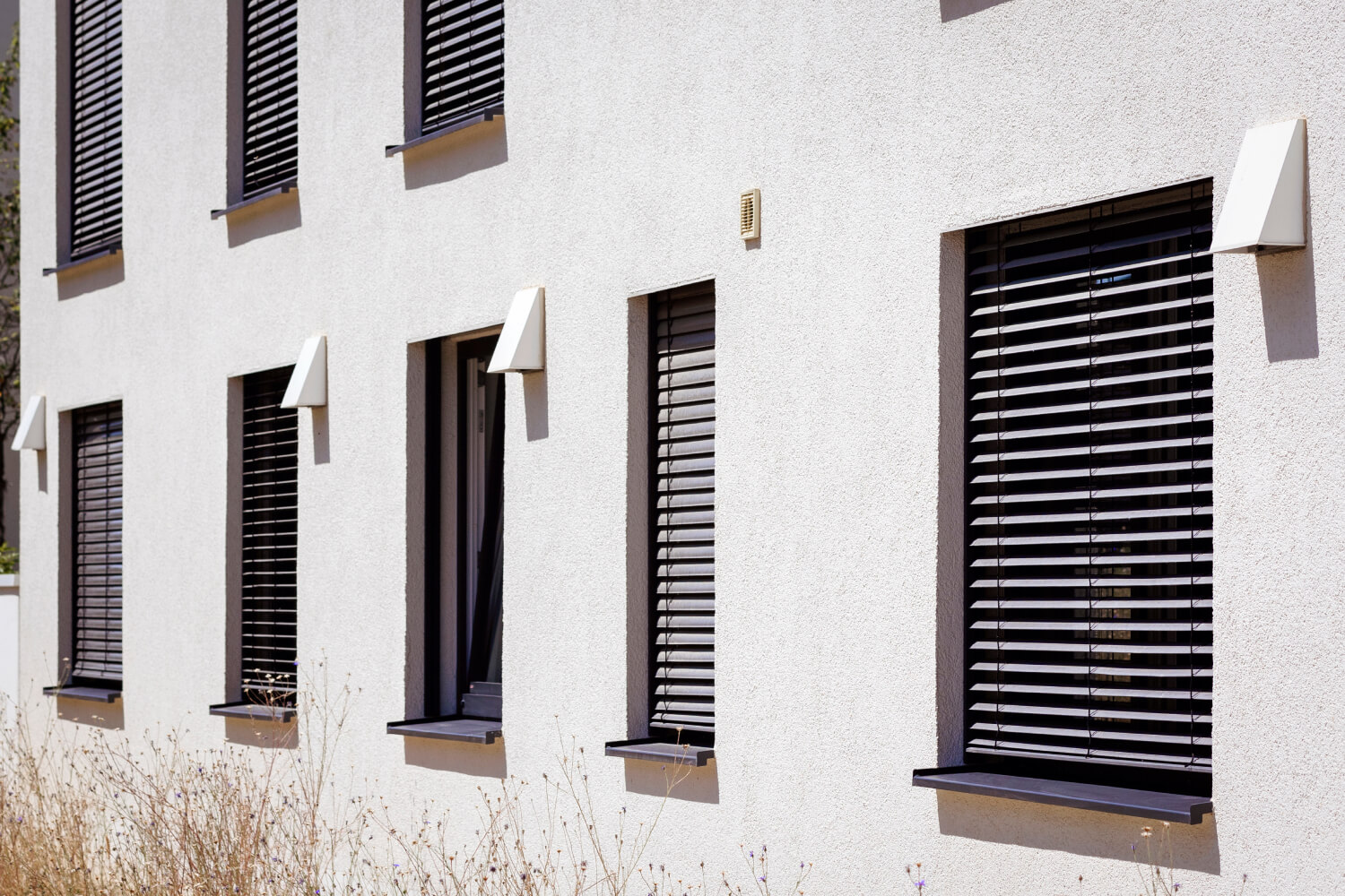 Außenansicht eines modernen Hauses mit Rollläden vor den Fenstern