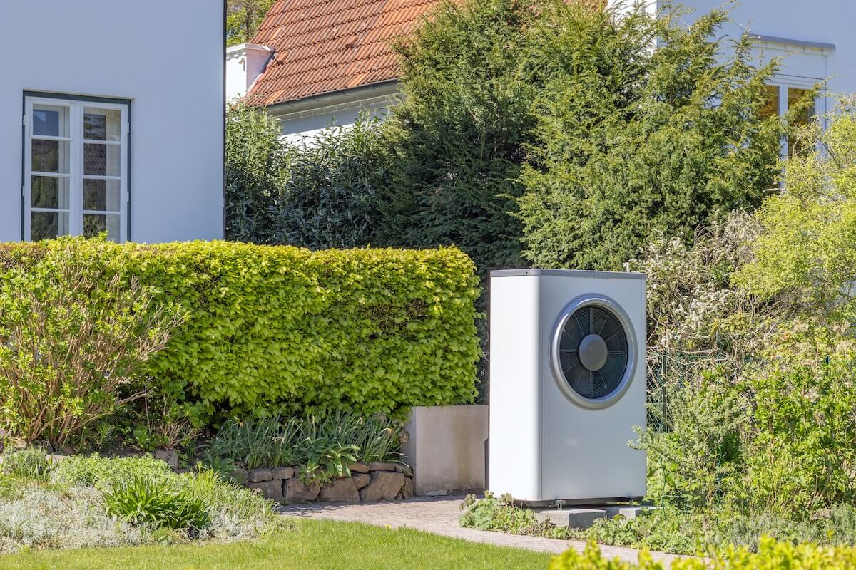 Außeneinheit einer Wärmepumpe im Garten eines Hauses