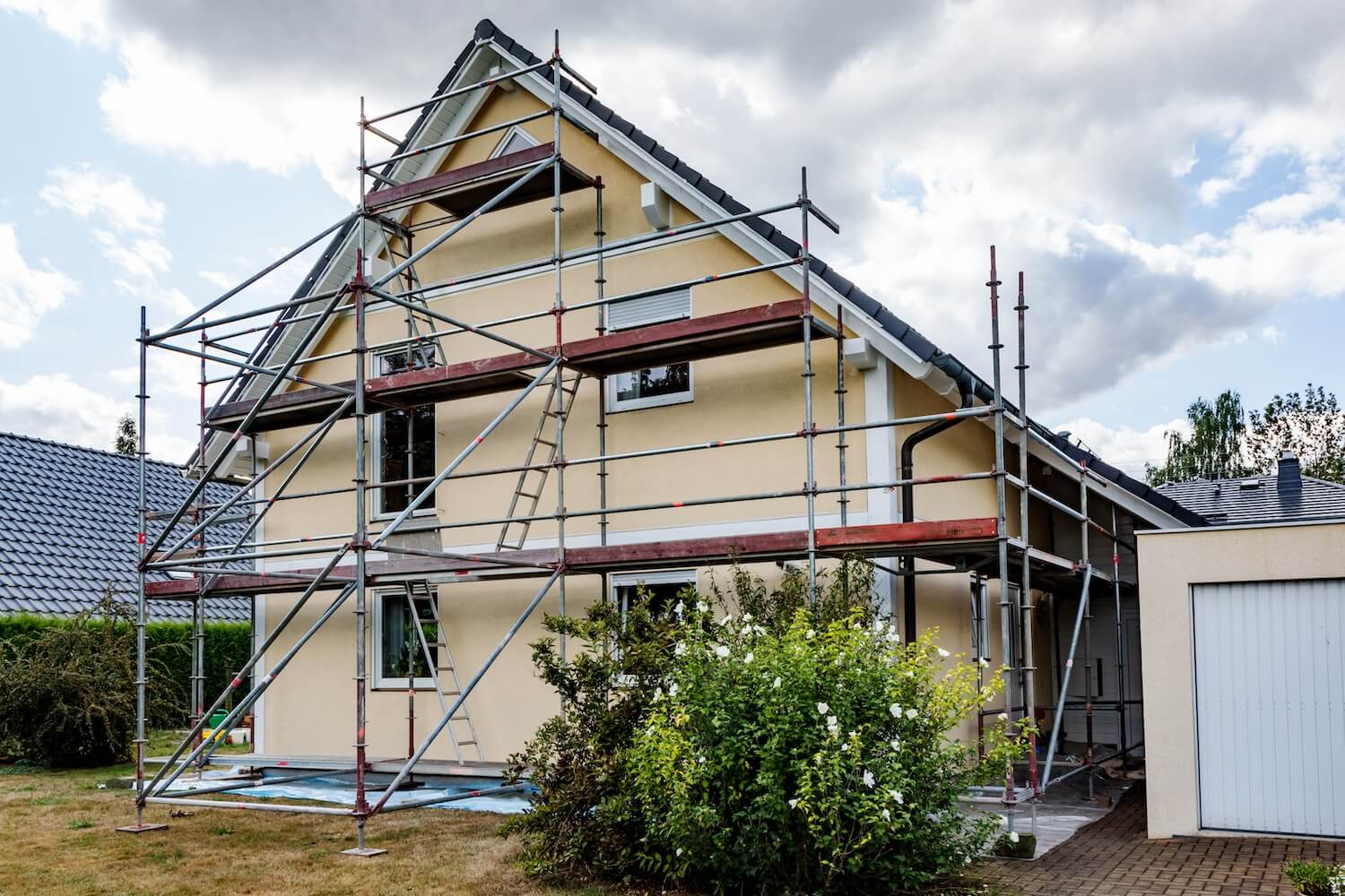 Ein Einfamilienhaus mit GerĂĽst, auf welchem Renovierungsarbeiten durchgefĂĽhrt werden.