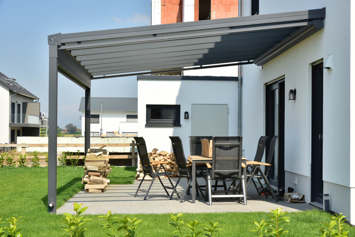 Terrassenüberdachung aus Aluminium, montiert an einem weißen Neubau
