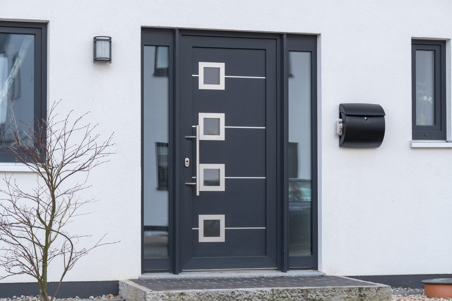 Schwarze Haustür aus Aluminium mit Glaselementen an der Seite