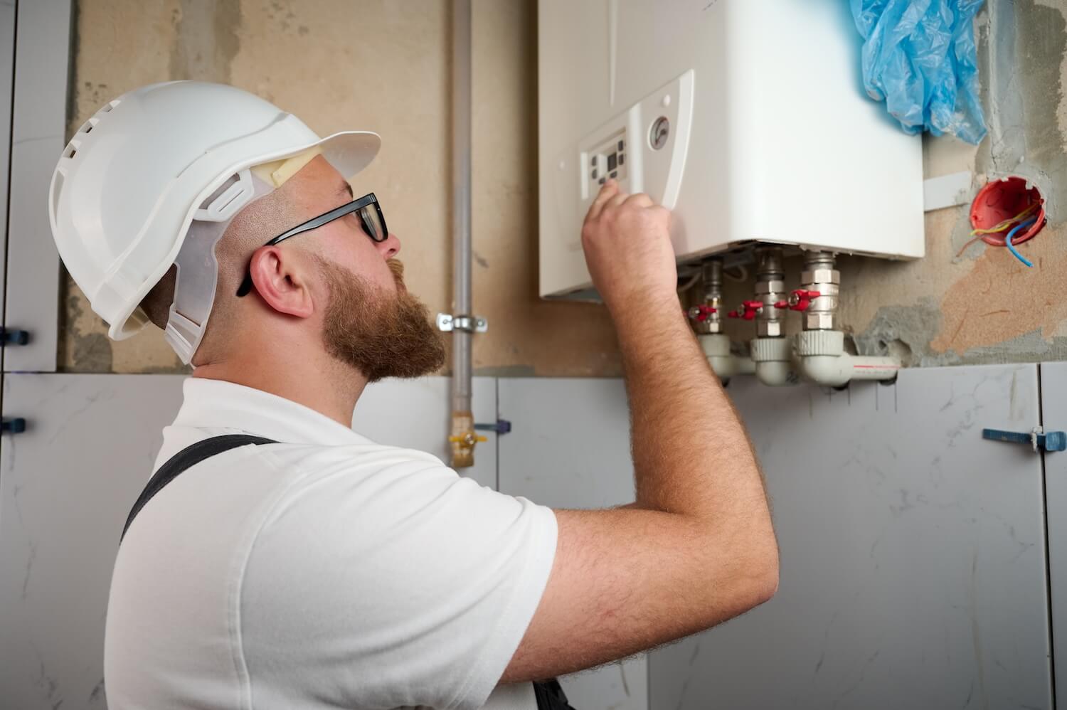Installateur mit Schutzhelm bei der Einstellung einer neuen Gasheizung im Innenbereich.