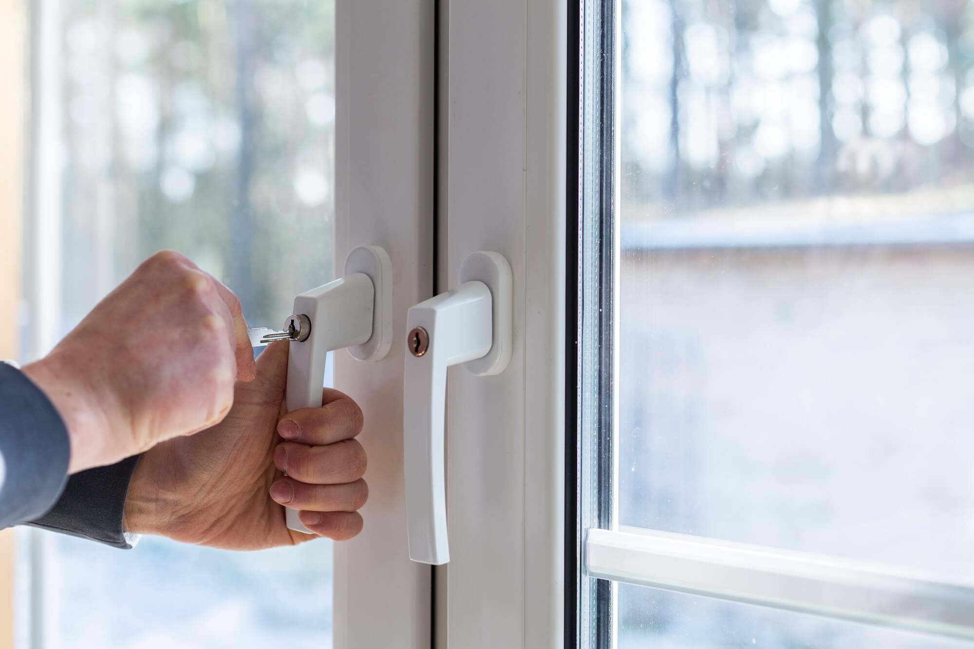 Ansicht auf zwei abschließbare Fenstergriffe, einer davon wird gerade aufgeschlossen.