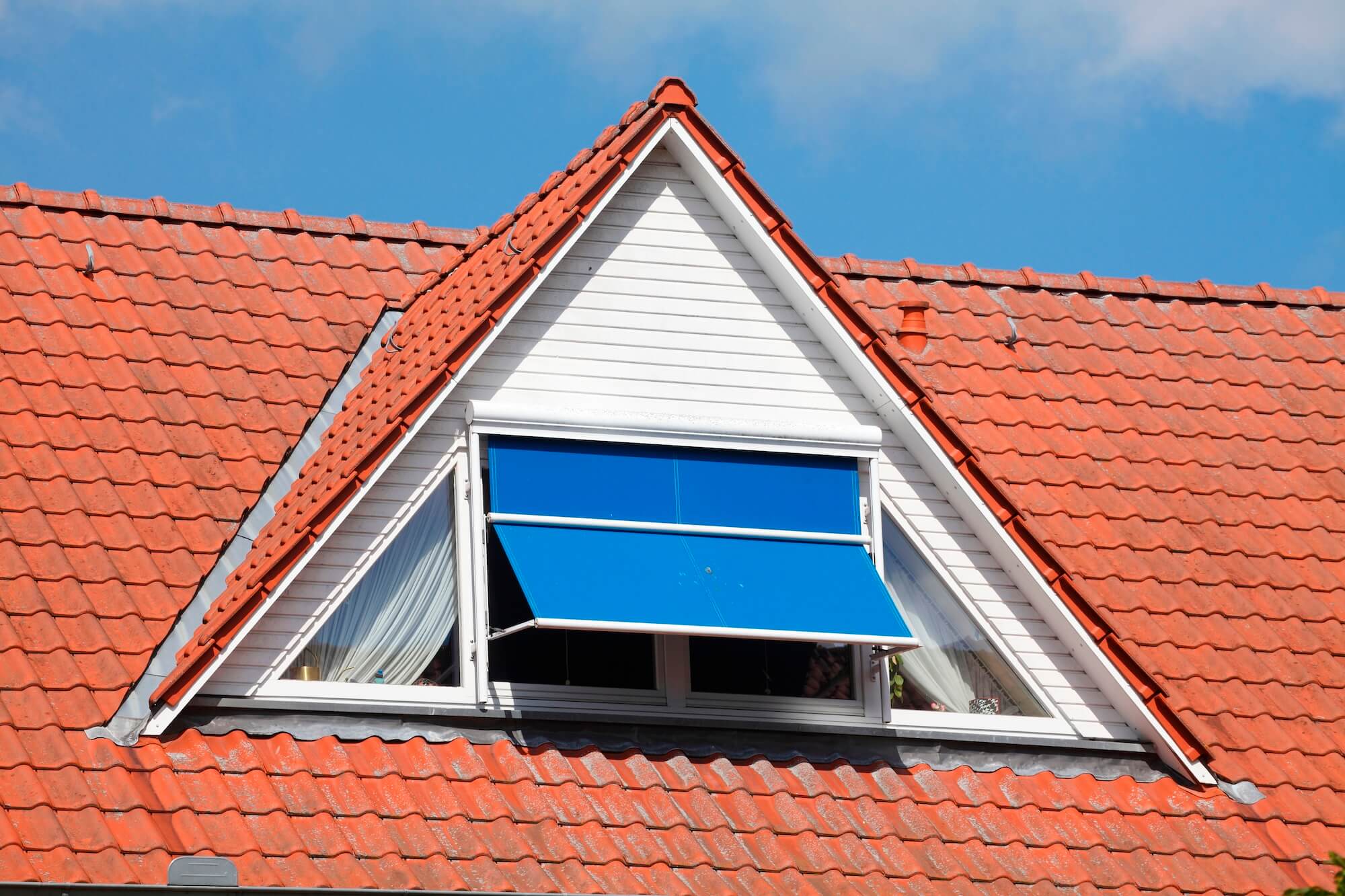 Ansicht auf eine Dachgaube mit Sonnenschutz am Fenster.