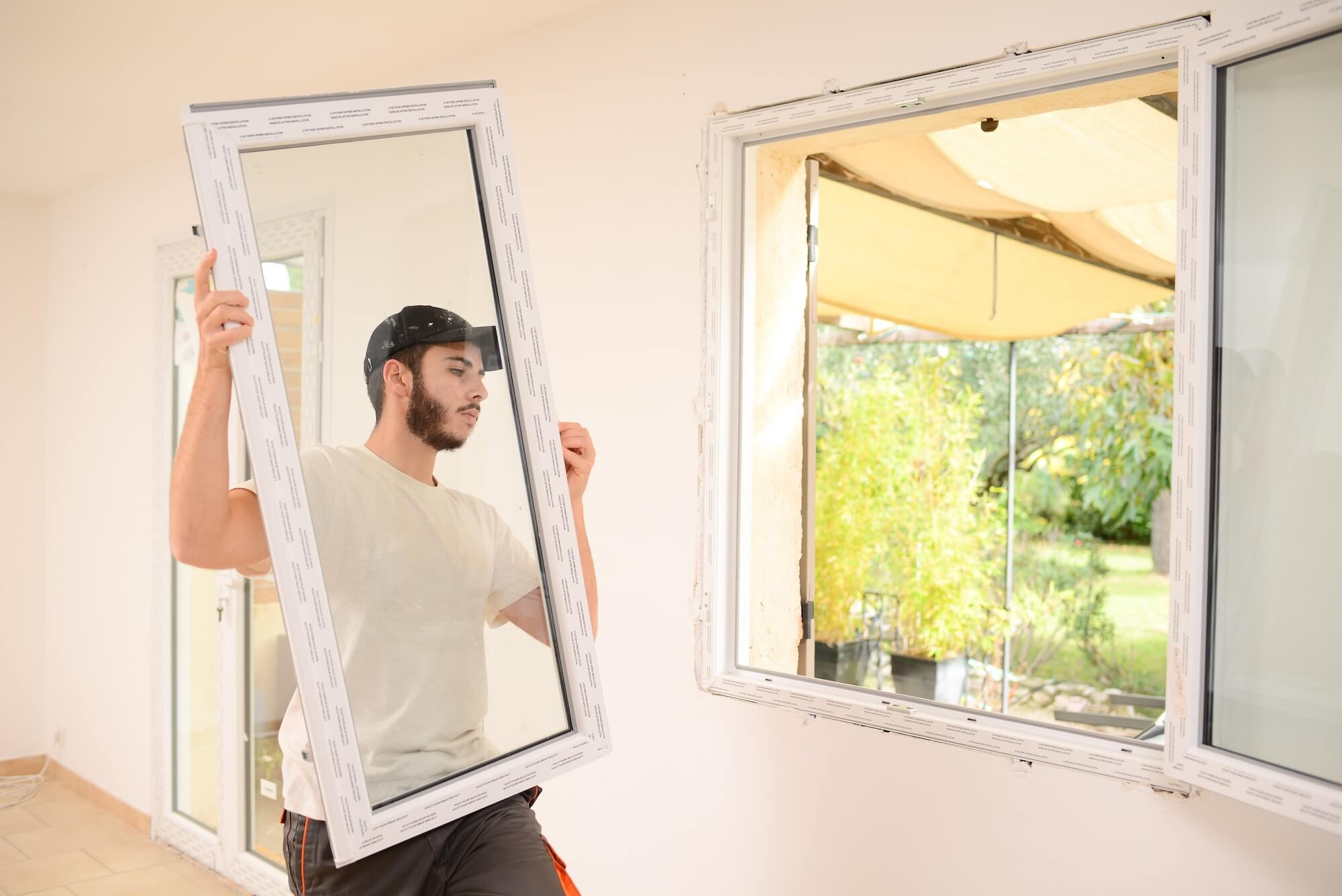 Ein Mechaniker trägt einen Fensterflügel zum Einbau in ein Fenster.