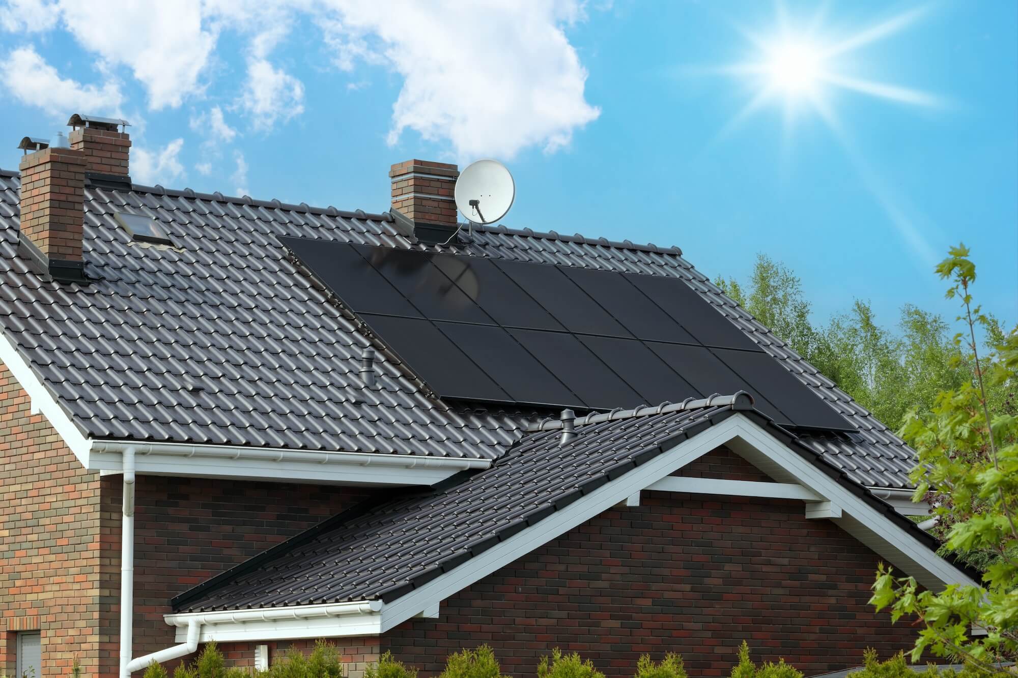 Ein Hausdach mit schwarzen Ziegeln und PV-Anlage auf dem Dach
