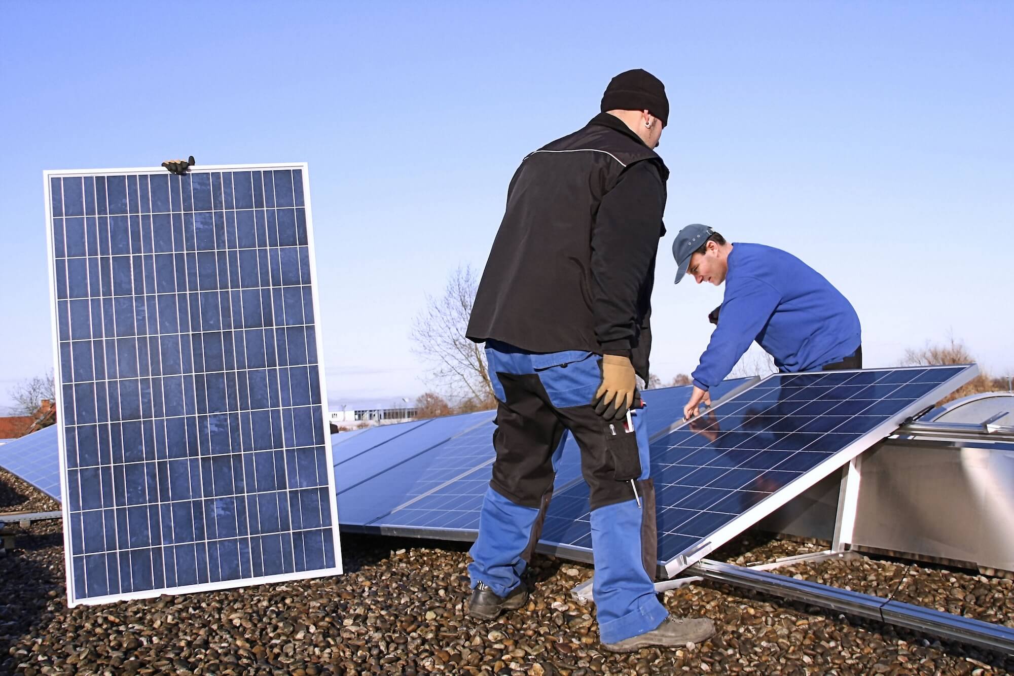 Zwei Handwerker bringen Solarpaneele an.