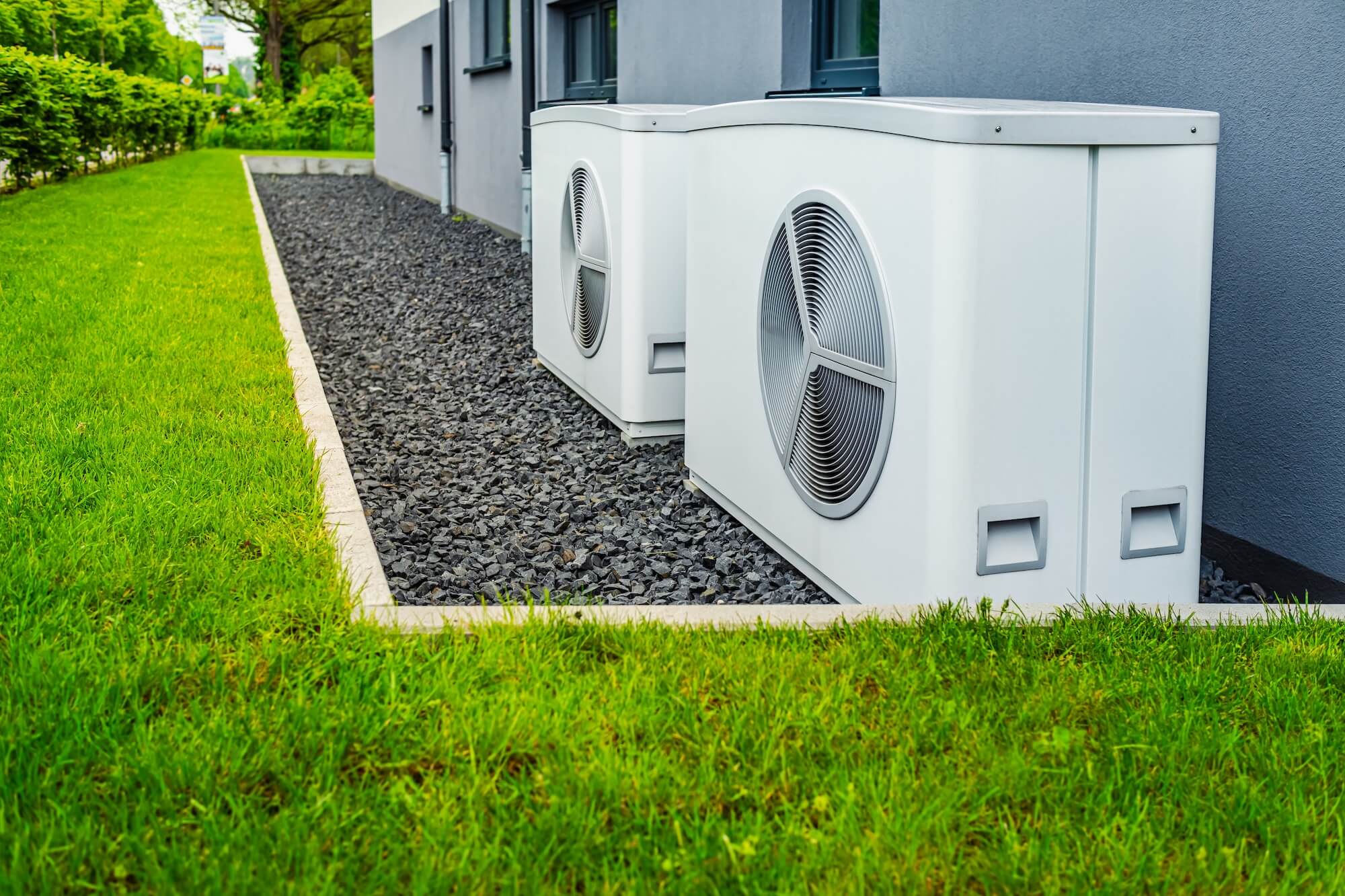 Zwei Wärmepumpen im Garten vor einem Haus