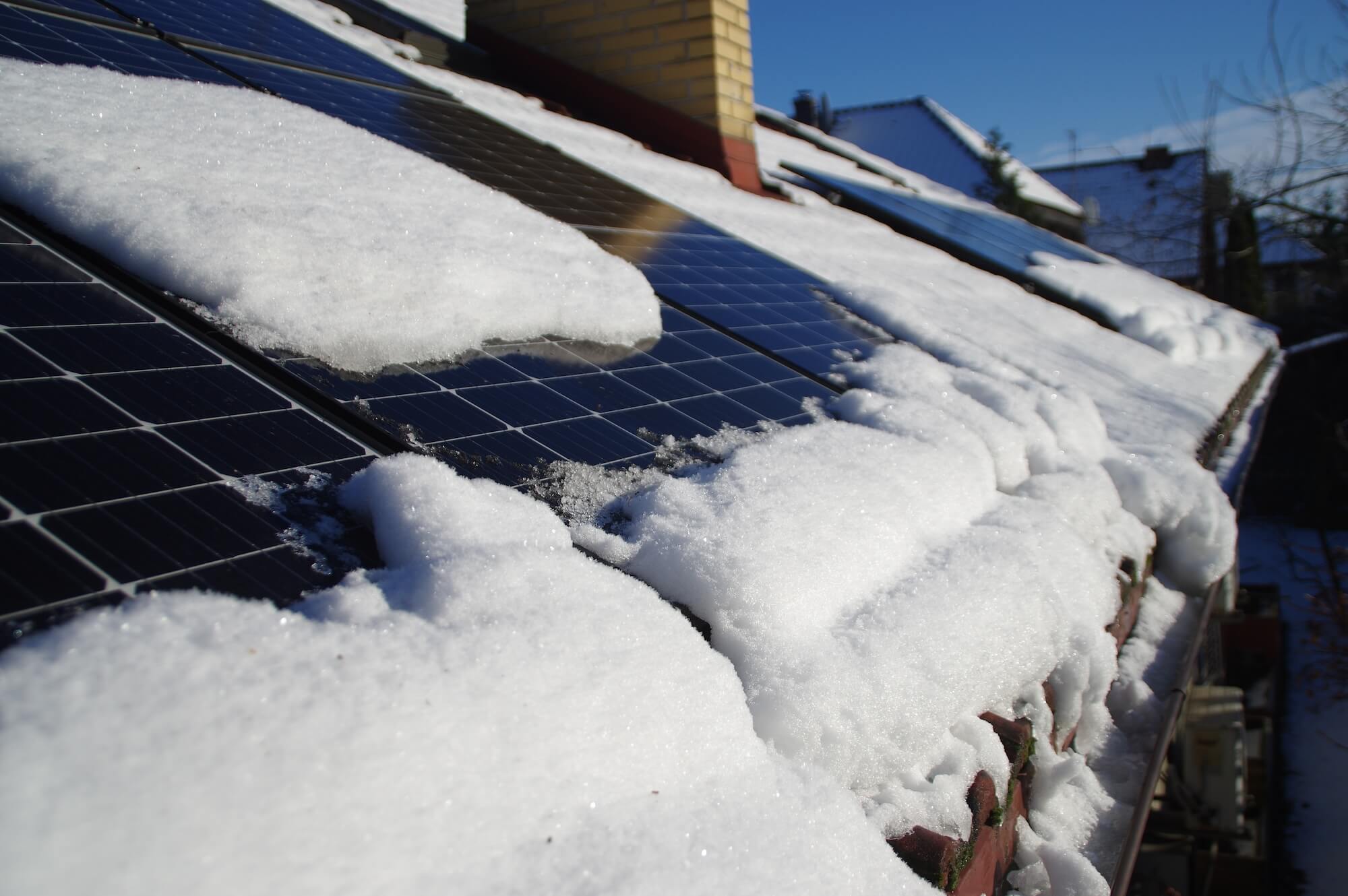Mit Schnee bedeckte Photovoltaikanlage auf einem Hausdach