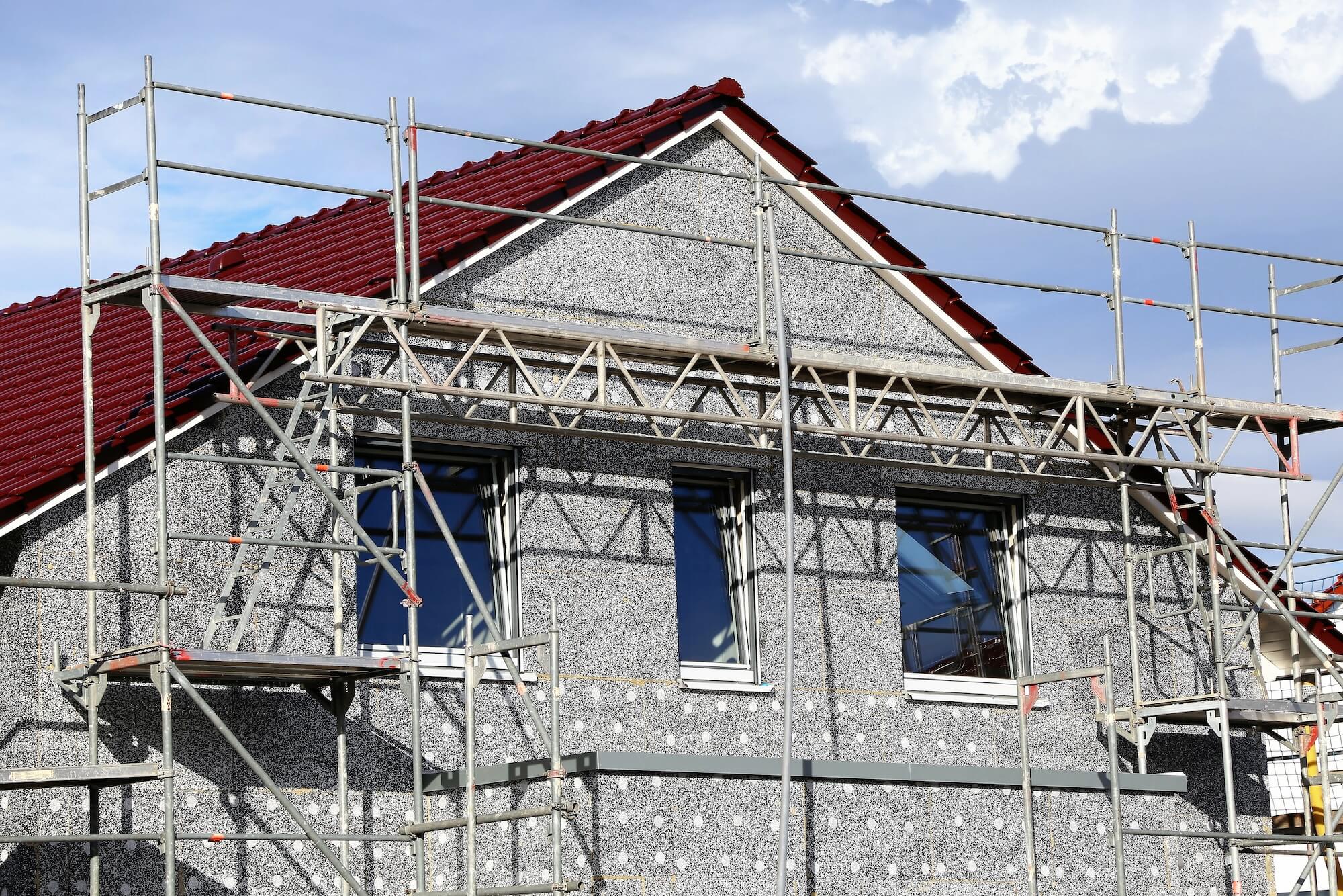 Die Fassade eines Wohnhauses wird gedämmt.