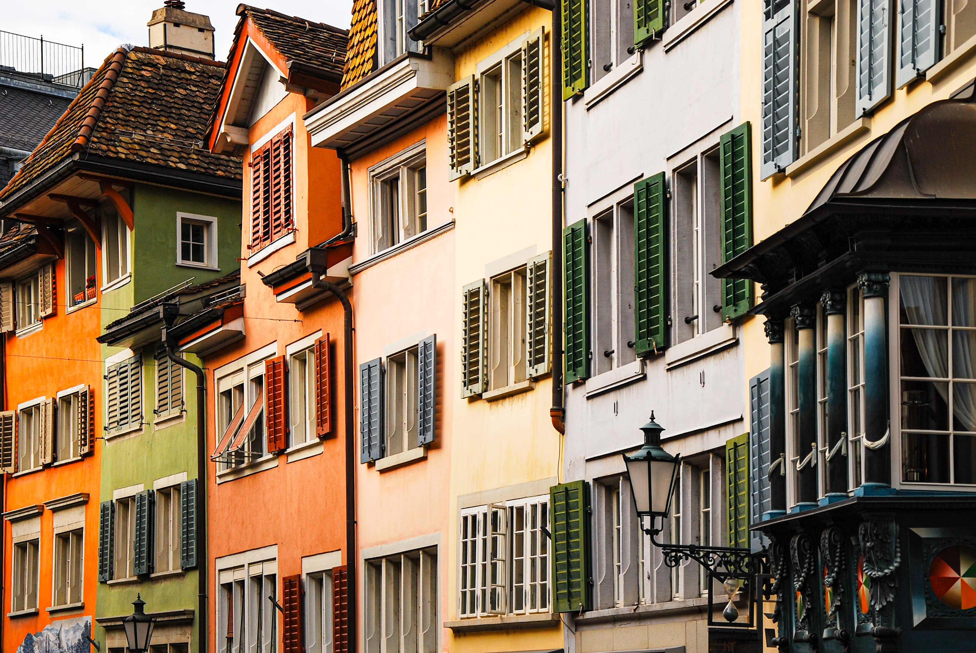 Bunt gestrichene Altbauten mit bunten Fensterläden stehen eng Haus an Haus.