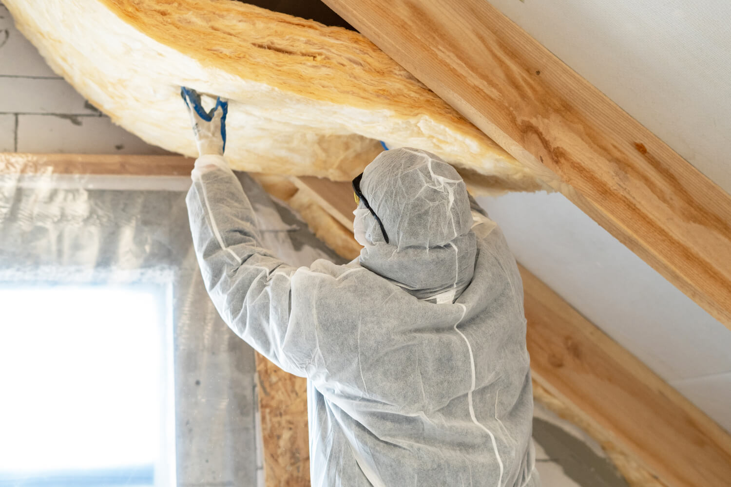 Handwerker bringt Dämmwolle zwischen den Dachsparren ein