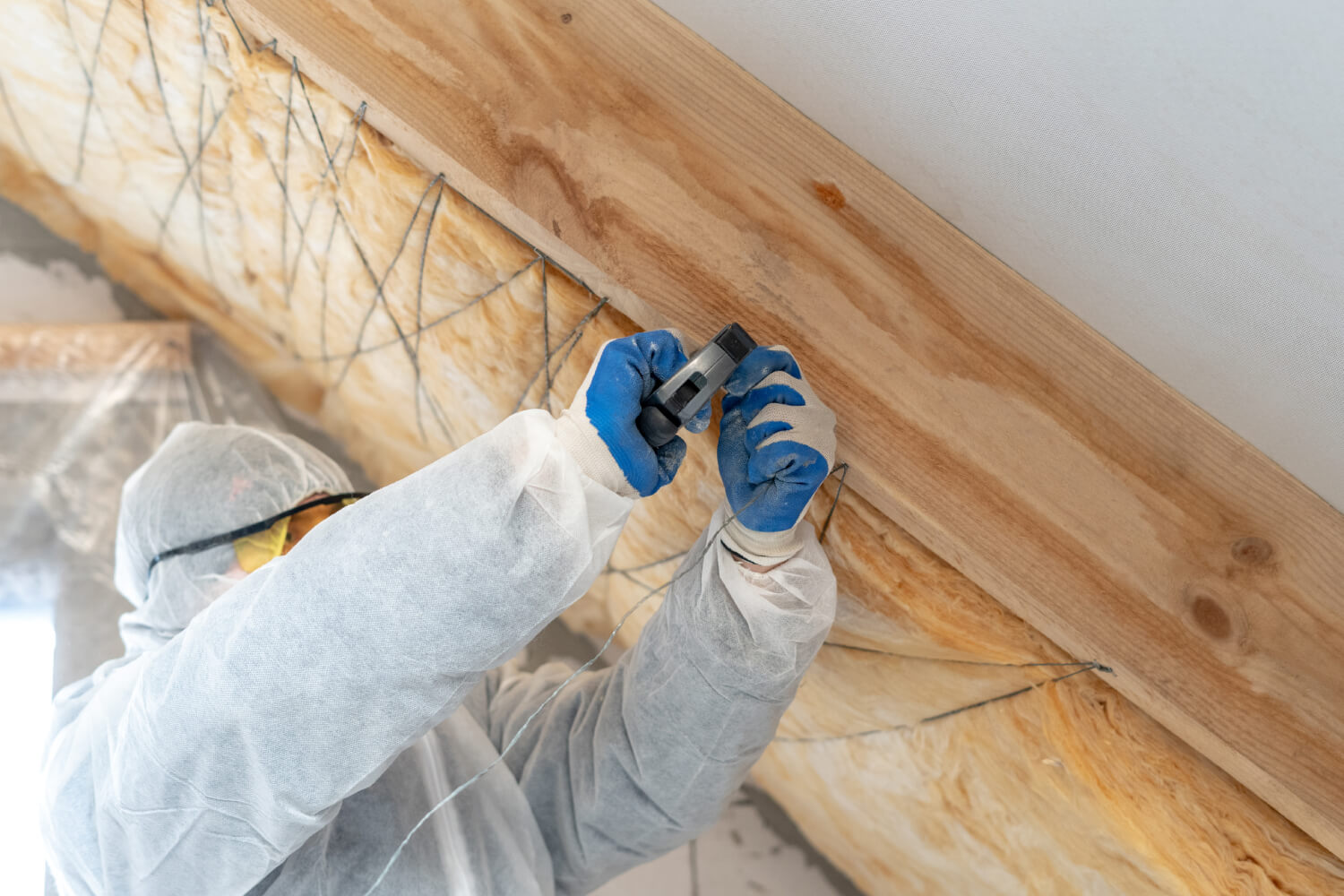 Handwerker bringt Untersparrendämmung im Dachstuhl an