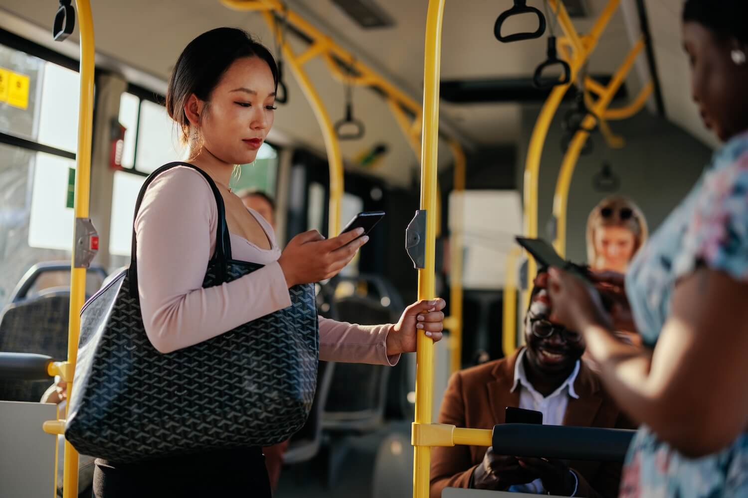 Frau im Bus überprüft über die Geofencing Heizung-App die Einstellungen ihrer Heizung.